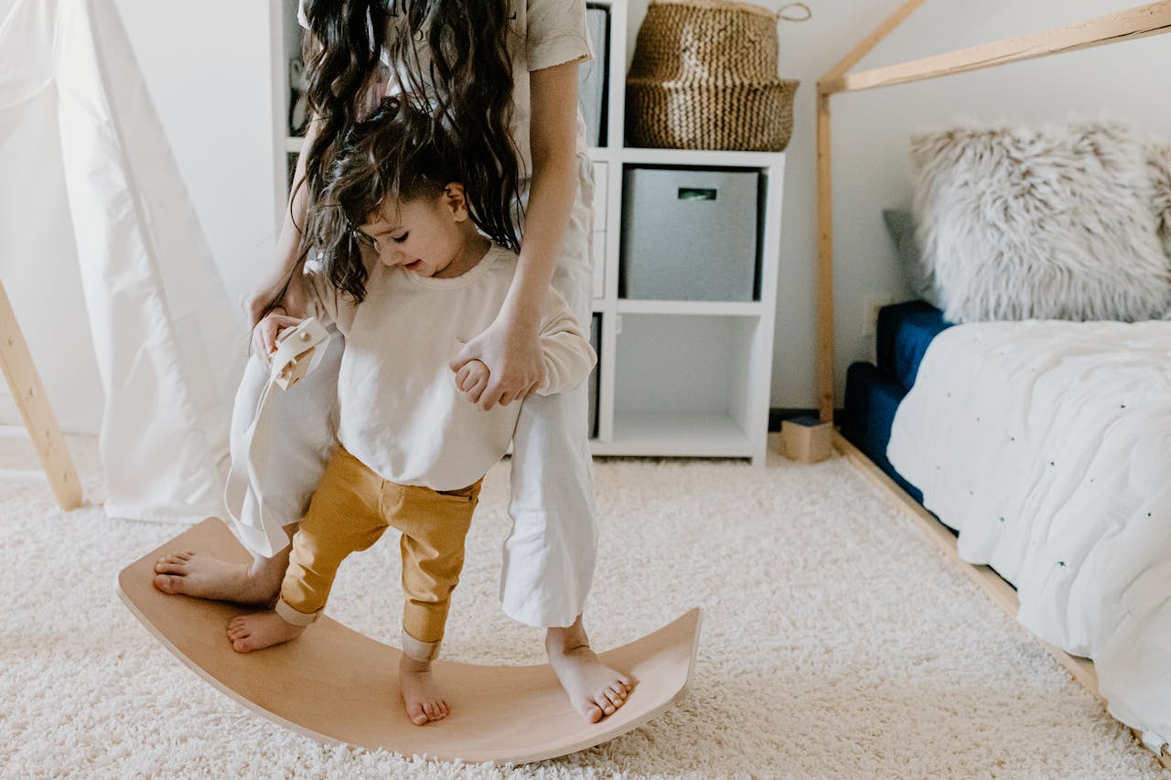 A Heartfelt Journey: How One Employer Found the Perfect Helper Through 1 Assist Agency Mother and son enjoy bonding time in a cozy bedroom on a wooden balance board.